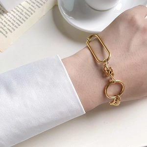 Close-up of a minimalist gold chain bracelet with oval links on a model's wrist