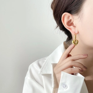 Close-up of elegant gold hollow heart-shaped drop earrings worn by a model