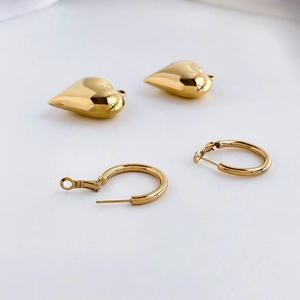 Detailed view of polished gold-tone heart pendants and matching circular hoop earrings