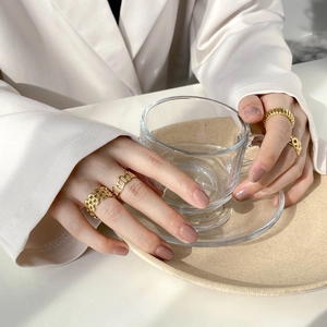 Lot de quatre bagues dorées ajourées et à maillons portées sur un verre