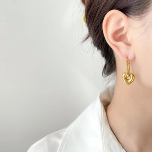 Close-up of a model wearing a hollow gold heart pendant earring with minimalist style