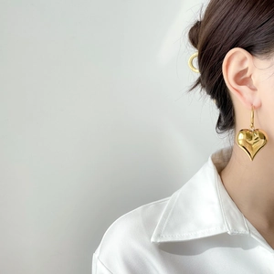 Detail of vintage gold hollow heart earrings on model with polished mirror finish
