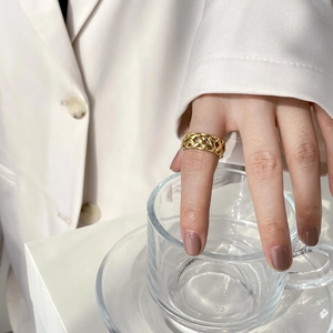 Gros plan d'une bague tressée dorée ajourée au doigt pour un look bijoux minimaliste