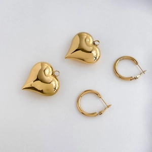 Macro shot of polished gold hollow heart pendants and matching classic hoop earrings