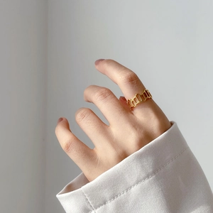 Détail d'une bague chaîne géométrique évidée dorée sur un mannequin en costume