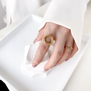 Close-up of gold irregular hollow lava ring and textured band stacked on a hand