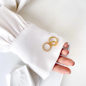 Close-up of golden lip-shaped geometric ring set on silk fabric and stone background
