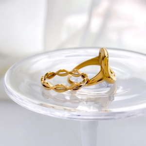 Abstract lip-shaped and curved gold rings on a glass tray with polished metallic finish