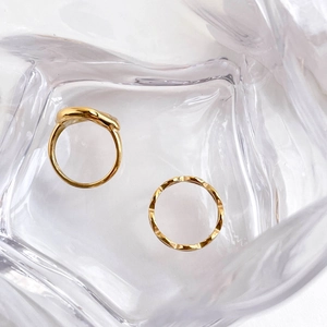 Detailed view of gold fluid lip rings set with wavy texture and faceted geometric patterns
