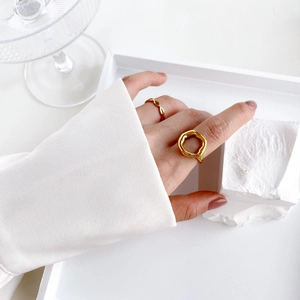 Detail of minimalist gold lip-shaped and wavy rings worn on fingers for a modern look