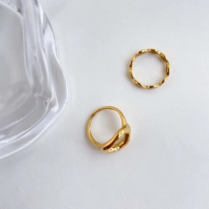 Detail view of two gold streamlined rings with hammered textures and smooth curves