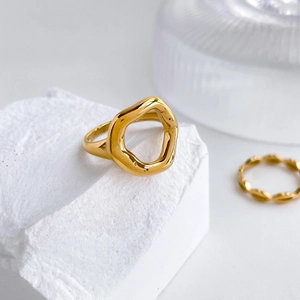 Macro detail of glossy golden abstract lip-shaped ring on a textured stone display