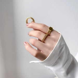 Detail of gold-plated cuban chain ring and thin minimalist band worn on fingers