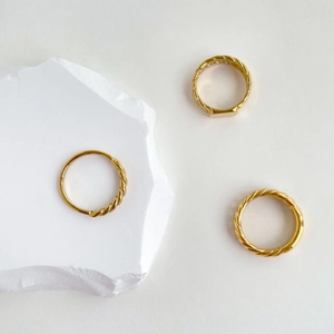 Detailed view of three-piece minimalist gold chain rings set on a white stone background