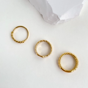 Detailed macro shot of three-piece gold twisted chain rings with polished mirror finish