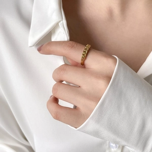 Detail of a gold chain link ring worn by a model in elegant white silk attire