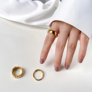 Detail of gold-plated ring set featuring Cuban chain link and twisted rope textures