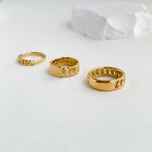 Detailed close-up of three gold chain design rings with elegant polished metal texture