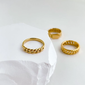 Detailed close-up of gold-plated chain rings with a polished finish on white stone