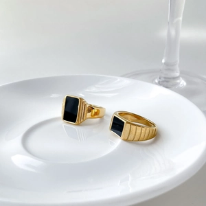 Gros plan de bagues chevalières dorées avec agate noire sur une assiette en céramique
