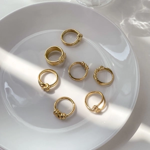 Macro shot of 7pcs gold twist rope rings set displayed on a white ceramic plate