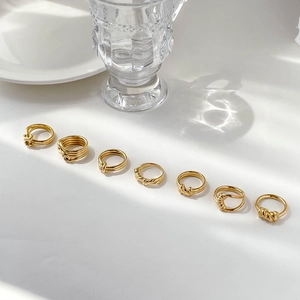 Detail view of 7-piece minimalist gold twisted rope rings set on a white surface