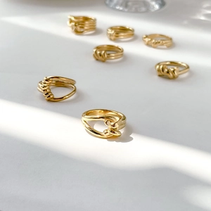 Detail of gold twisted knot rings showcasing elegant metallic textures and shadow play