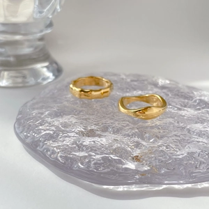 Close-up of golden bamboo texture and wavy minimalist rings on a glass tray