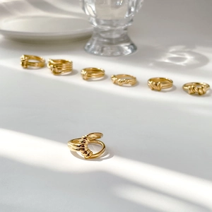 Detail of gold twisted rope rings displayed under natural sunlight with shadows