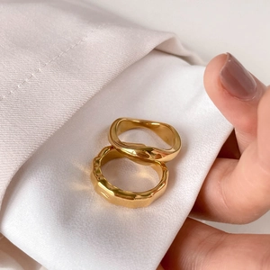 Detailed close-up of two gold textured rings with organic lava patterns on white silk