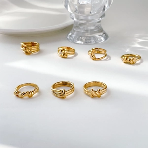 Collection of minimalist twisted rope rings in gold finish displayed on white porcelain