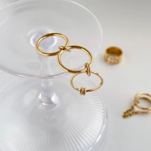 Detail von dreilagigen goldenen Gliederringen mit Quastenkette auf Glasständer