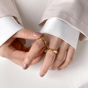 Detail of a gold bamboo-style faceted ring paired with a sleek minimalist band on a finger