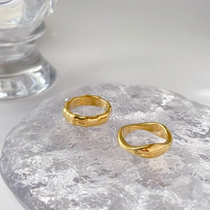 Detail of two gold-finish vintage rings featuring hammered texture and wavy wave design