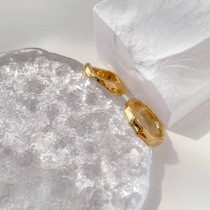 Bamboo-style gold rings with irregular texture on white geometric stone and glass