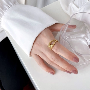 Close-up of golden twisted rope ring worn on finger with a stylish white shirt cuff