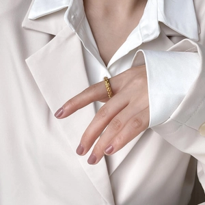 Detail of golden double-layer lava texture ring on model's index finger in neutral tones