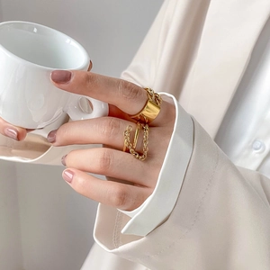 Minimalistische goldene mehrlagige Gliederkettenringe für Damen an Hand mit Kaffeetasse