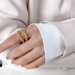 Detailed view of two textured gold rings with a hammered crater finish on fingers