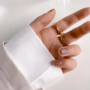 Close-up of stacked gold wave rings with lava texture on fingers in minimalist style