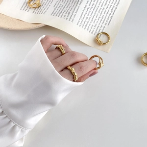 Detail of multiple gold twisted rope rings worn and scattered on a white background