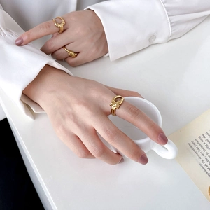 Stackable gold braided rings and interlocking bands for women on hand with a coffee mug