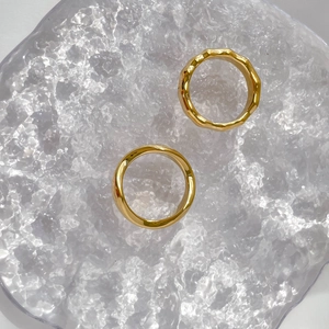 Detail view of smooth polished and hammered gold bamboo rings on a textured glass tray