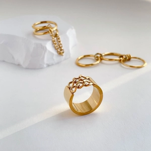 Detailansicht goldener mehrlagiger Kettenringe und Quastenring auf weißem Stein