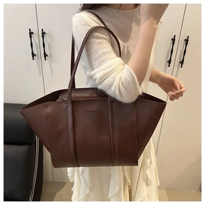 Shoulder view of large brown faux leather tote bag with FASHION logo and secure zipper