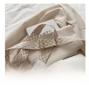 Detail of wide geometric woven shoulder strap with gold adjustable buckle and hardware