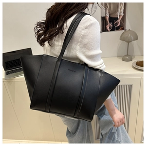 Close-up of matte leather tote bag with FASHION logo worn over the shoulder