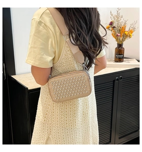 Detailed view of champagne crossbody bag with silver studs and wide fabric strap