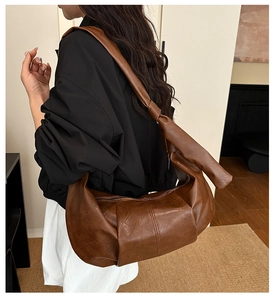 Close-up of a large dark brown pleated leather dumpling bag with knotted shoulder strap