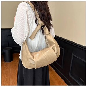Detailed back view of a beige ruched croissant bag with stylish knotted shoulder strap